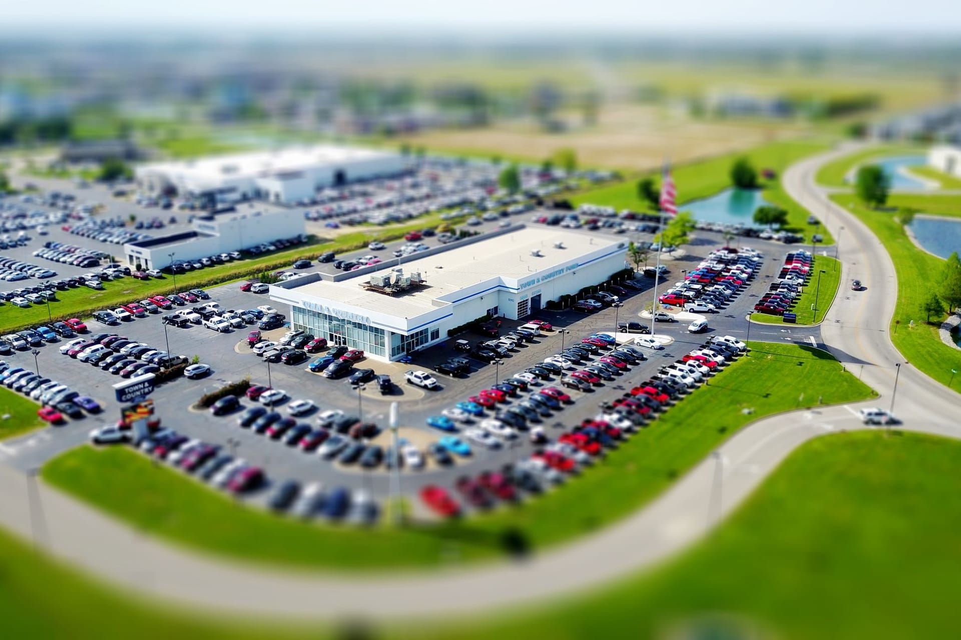 Aerial view of a car dealership building surrounded by rows of vehicles for sale