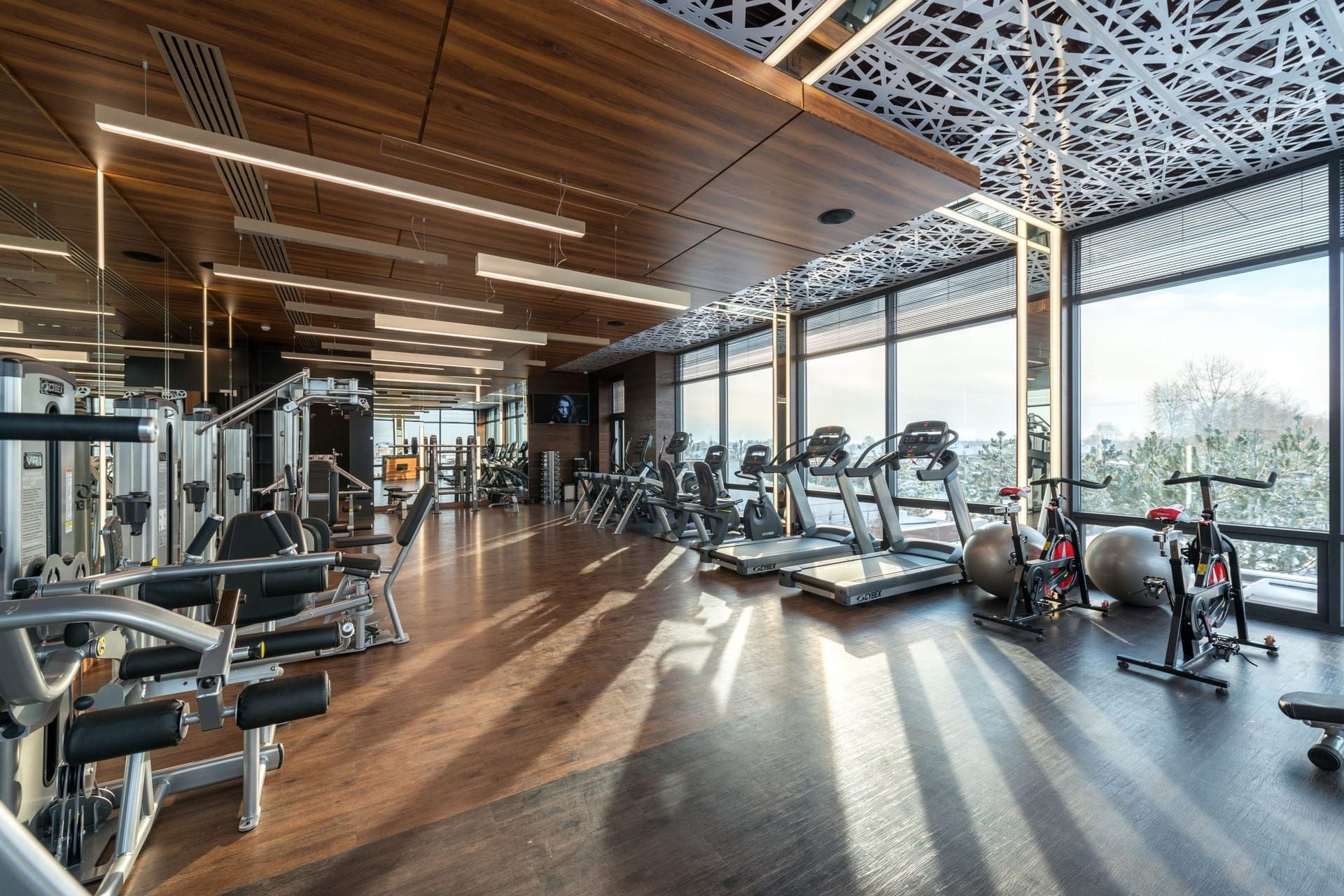 Fitness center with cardio machines and weights by floor-to-ceiling windows
