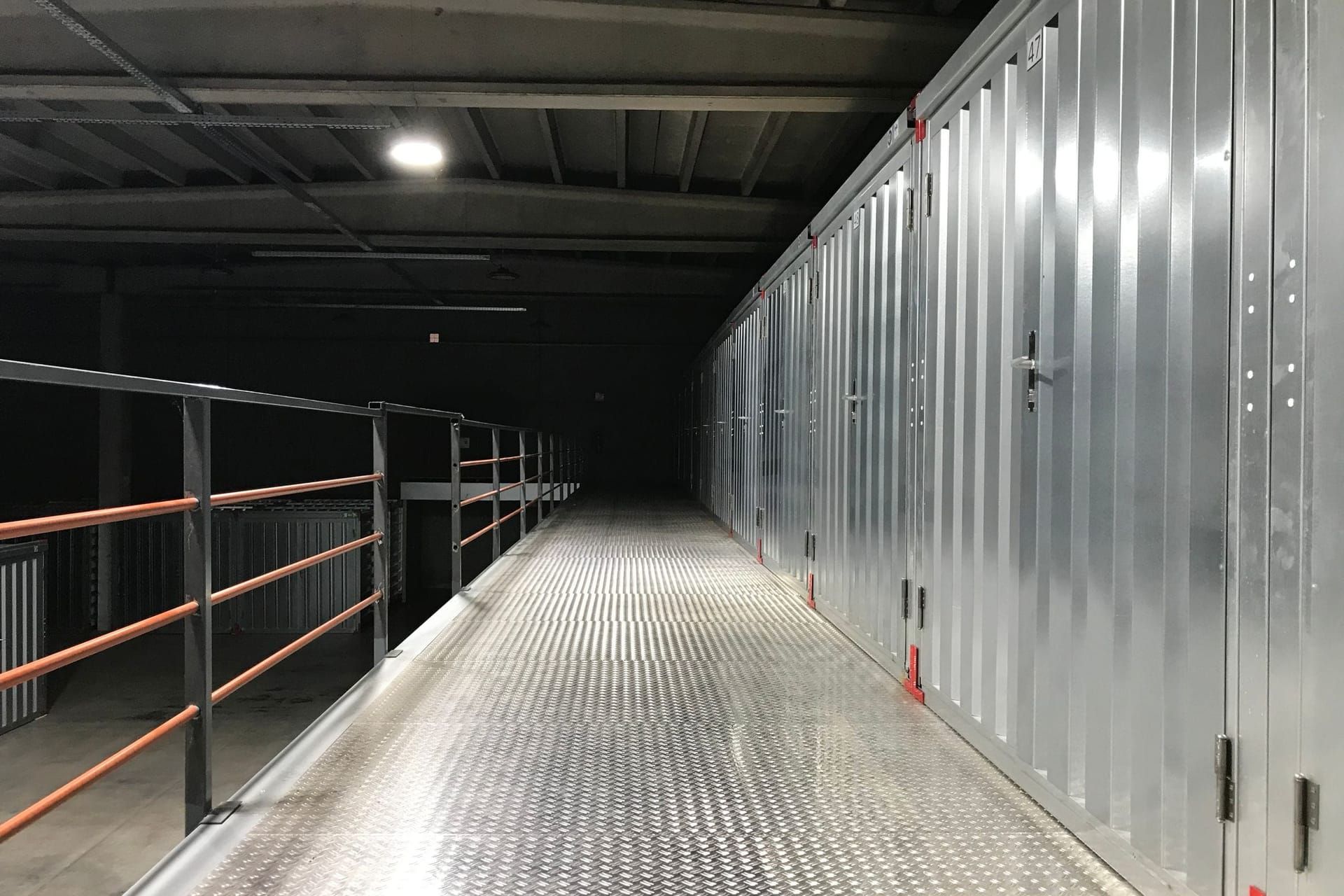Row of metal self-storage units along an indoor corridor