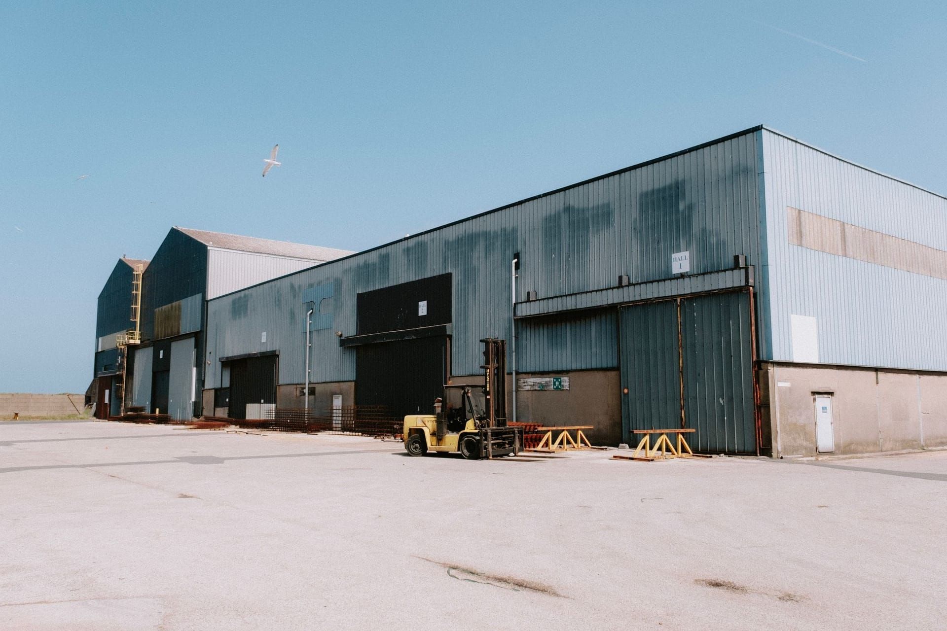 Large metal warehouse with loading doors and a forklift out front